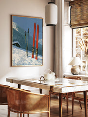 Vintage red skis and poles in deep snow with a mountain cabin and forest in the background, in a styled room mockup
