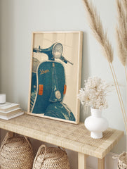 Illustrative vintage blue-green Vespa scooter wall art print with headlight and 'Vespa' logo, in an alternate framed mockup