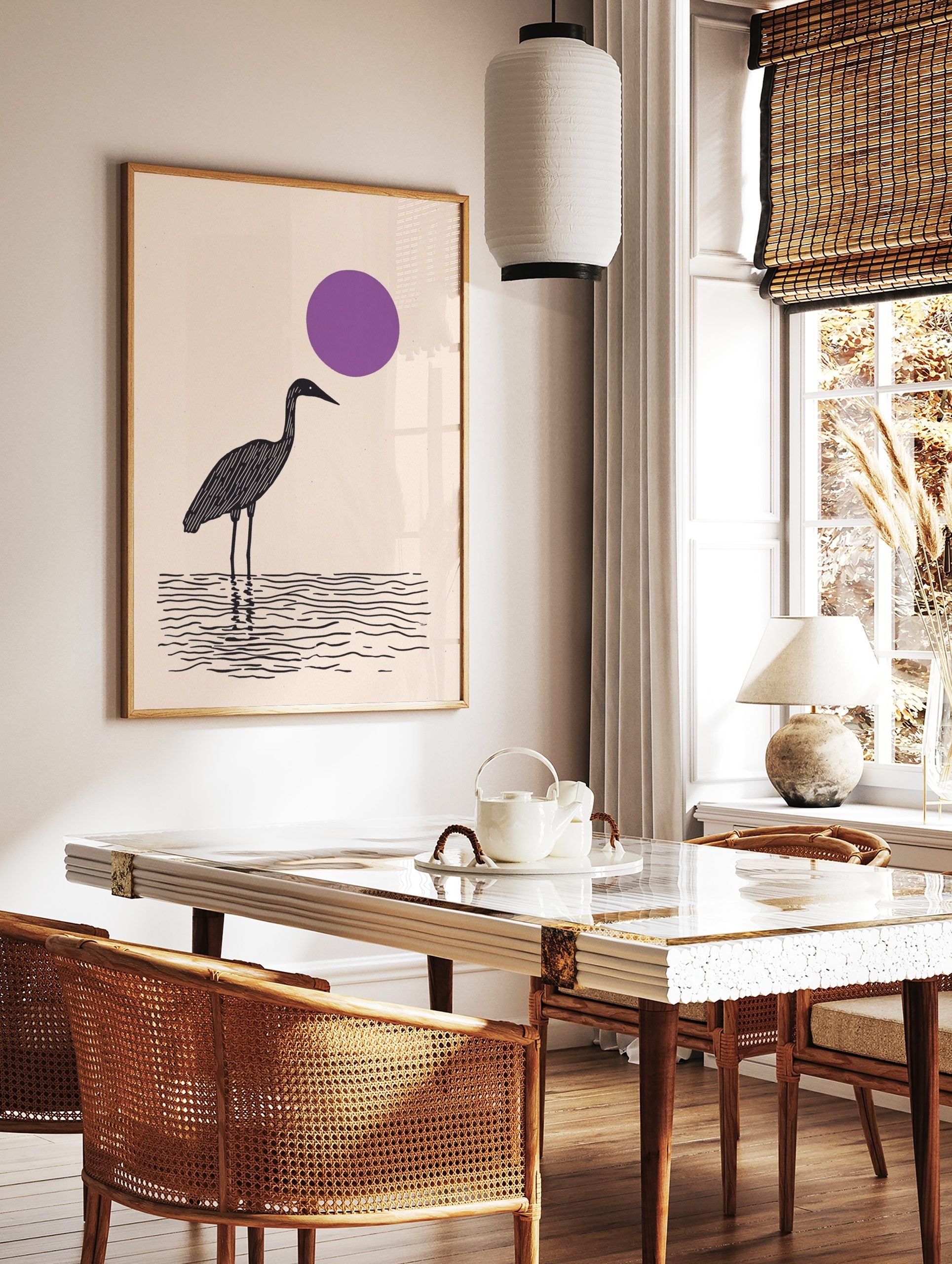 Minimalist black wading bird standing in water with a large purple sun on a beige background, in a styled room mockup