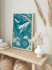 Linocut-style illustration of a whale swimming through a field of flowers in teal and cream, in an alternate framed mockup