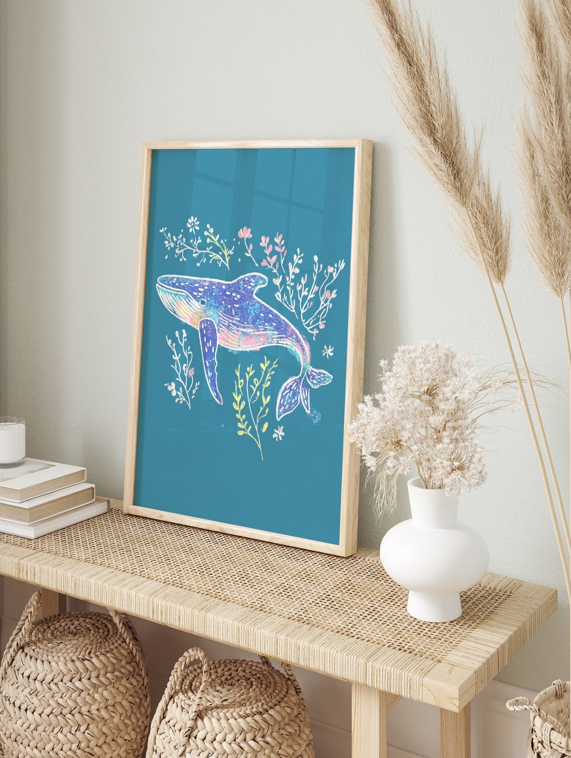 Illustrative blue whale art print with pink, yellow, and white seaweed on a teal background, in an alternate framed mockup