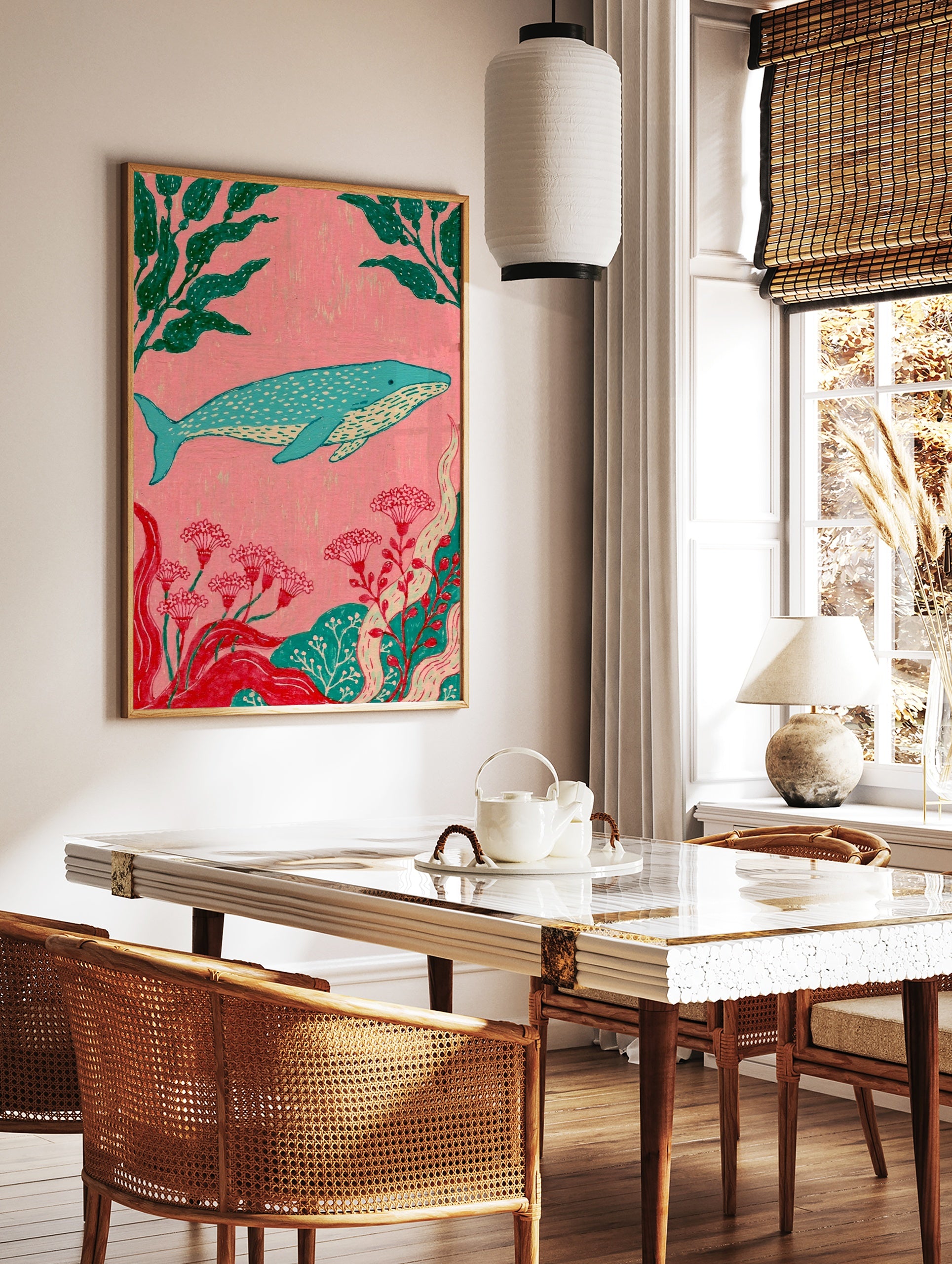 Stylized blue whale illustration with green kelp and red flowers on a pink background, ocean-themed, in a styled room mockup