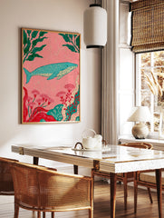 Stylized blue whale illustration with green kelp and red flowers on a pink background, ocean-themed, in a styled room mockup