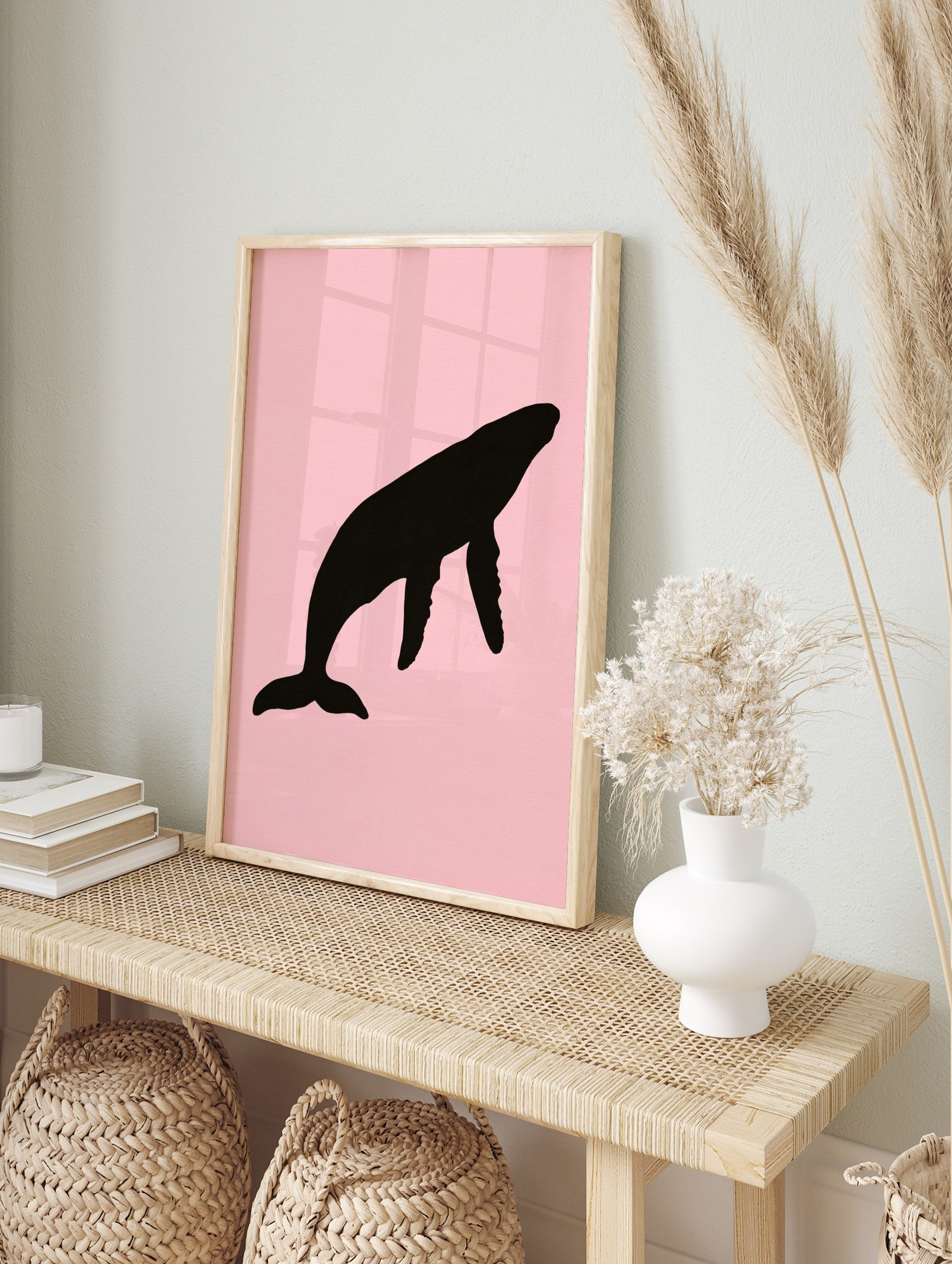 Black humpback whale silhouette illustration on a solid soft pink background, minimalist wall, in an alternate framed mockup