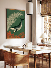 Stylized illustration of a speckled whale swimming past cream foliage on a dark green background, in a styled room mockup