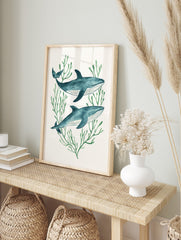 Illustrative watercolor print of two blue whales swimming among green seaweed on a white, in an alternate framed mockup