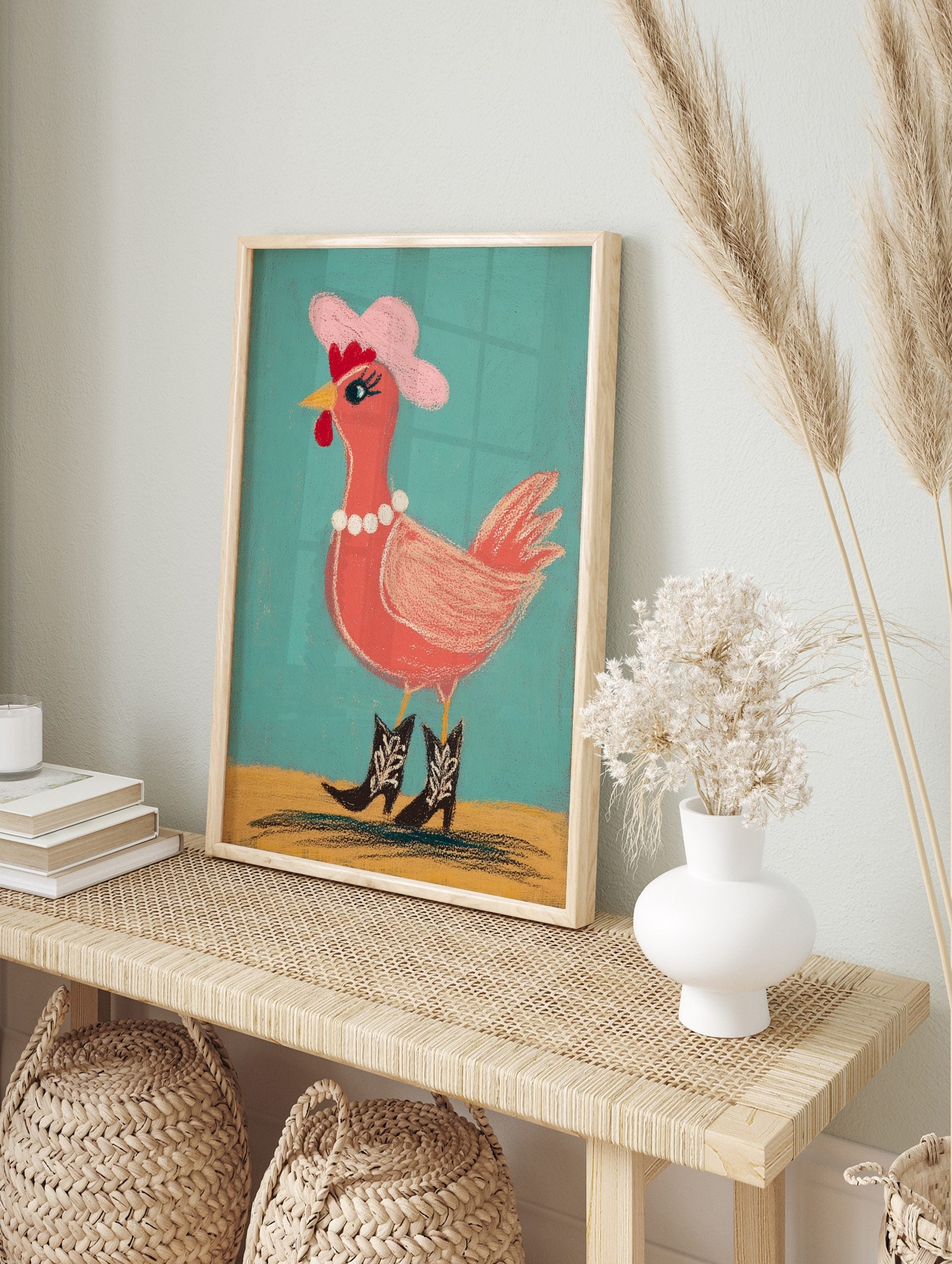 Illustrative chicken wearing pink cowboy hat, pearl necklace, and cowboy boots against teal, in an alternate framed mockup