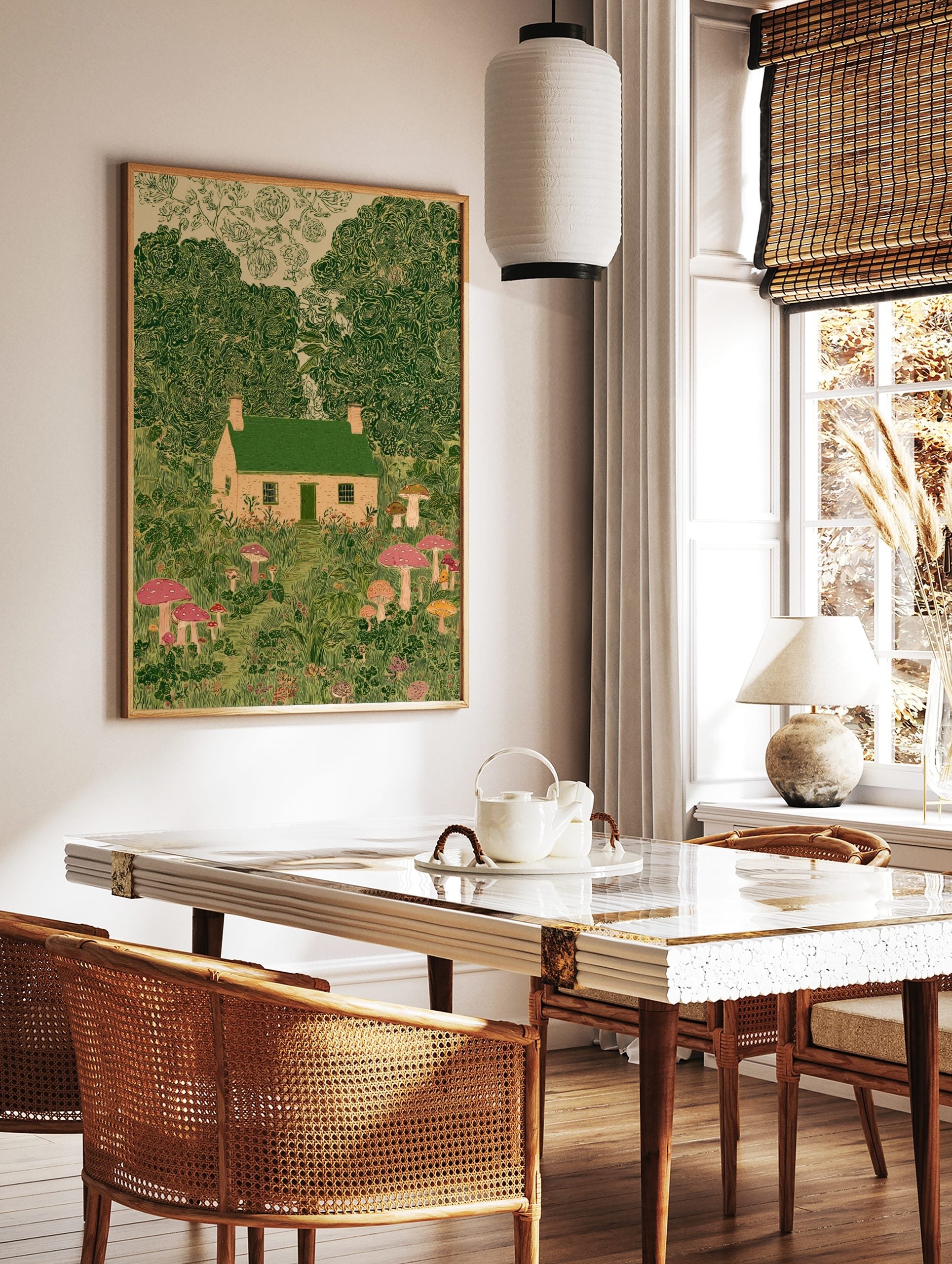 Illustrative print of a whimsical cottage with green roof, surrounded by lush green trees and, in a styled room mockup
