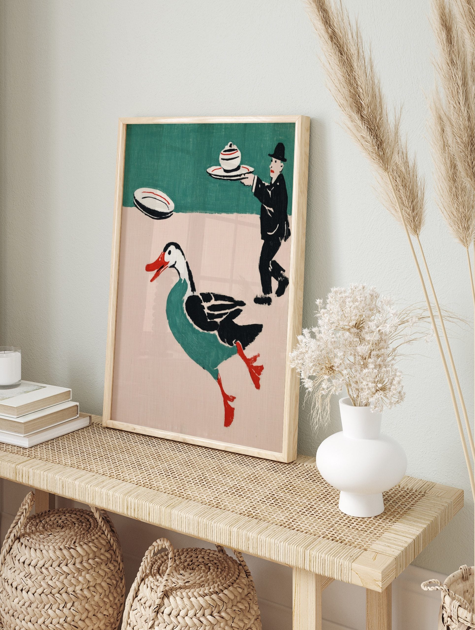 Whimsical illustrative print of a running teal duck with red beak and a waiter carrying a, in an alternate framed mockup