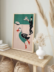 Whimsical illustrative print of a running teal duck with red beak and a waiter carrying a, in an alternate framed mockup