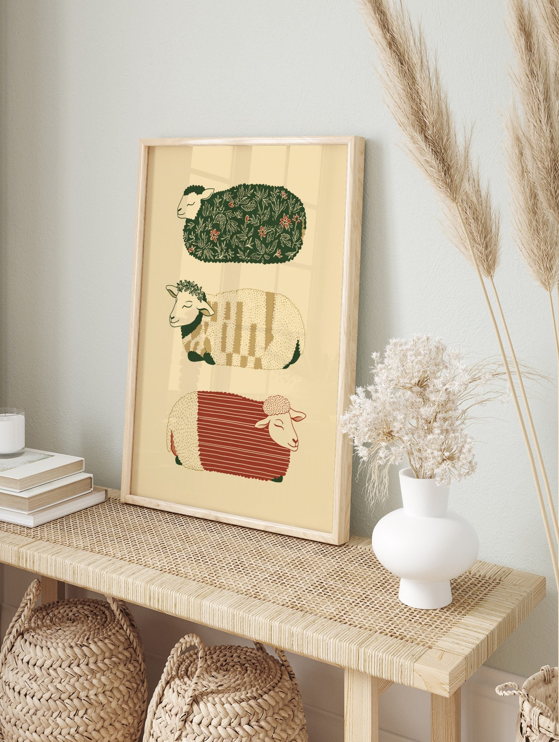 Three illustrative sheep with patterned fleeces in green, red, and beige, stacked vertically, in an alternate framed mockup