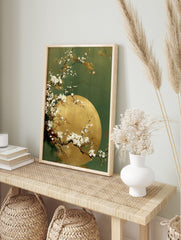 White cherry blossom branches curving over a golden full moon against a deep green, in an alternate framed mockup