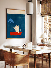 Illustrative art print featuring a white cat waving from a red boat at a blue dolphin against a, in a styled room mockup