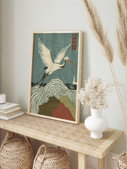 Japanese woodblock print of a white crane flying over swirling stormy waves and rain, with a, in an alternate framed mockup