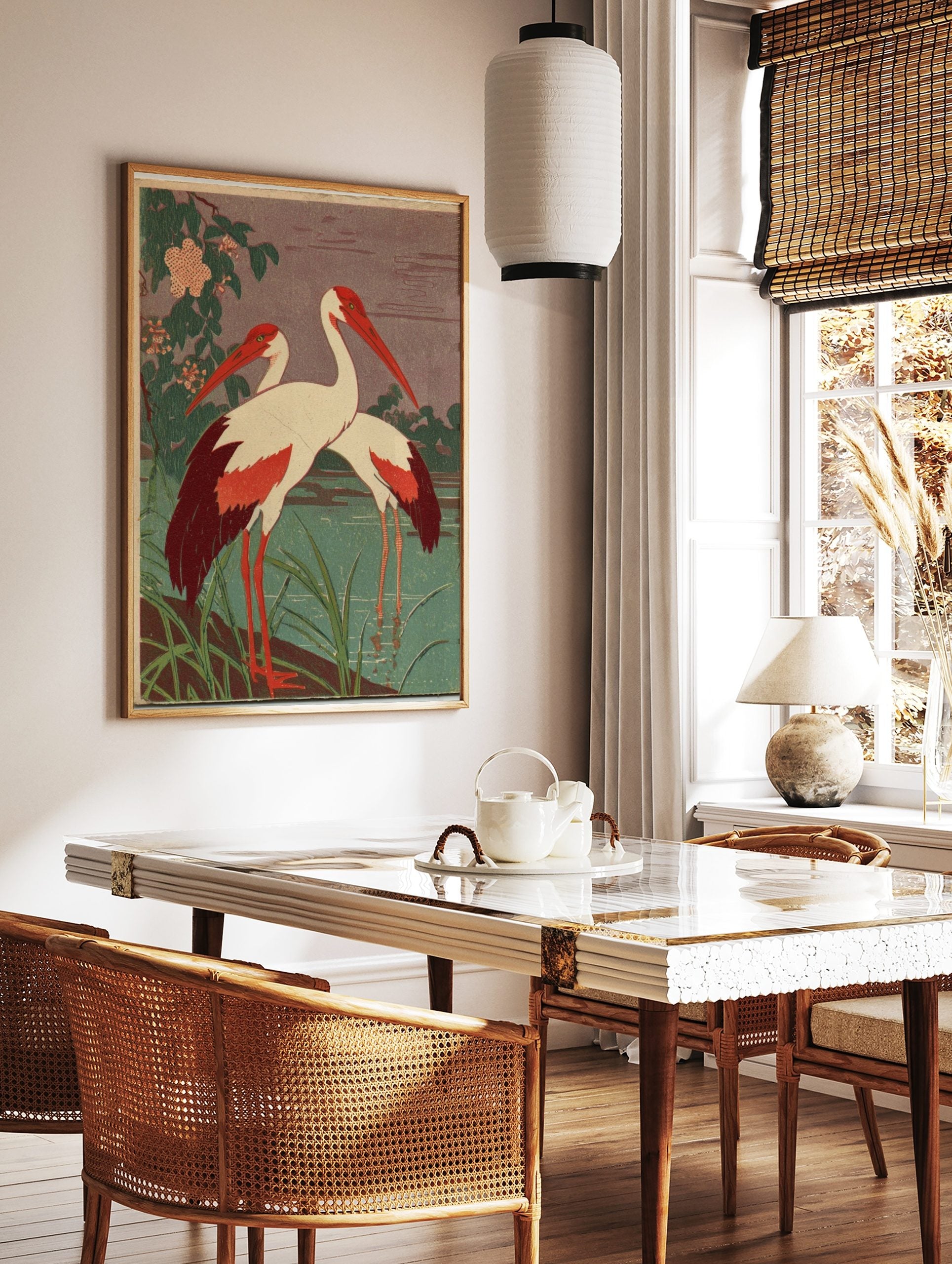 Two white cranes with red heads and wing tips standing in green water with foliage and pink flowers, in a styled room mockup