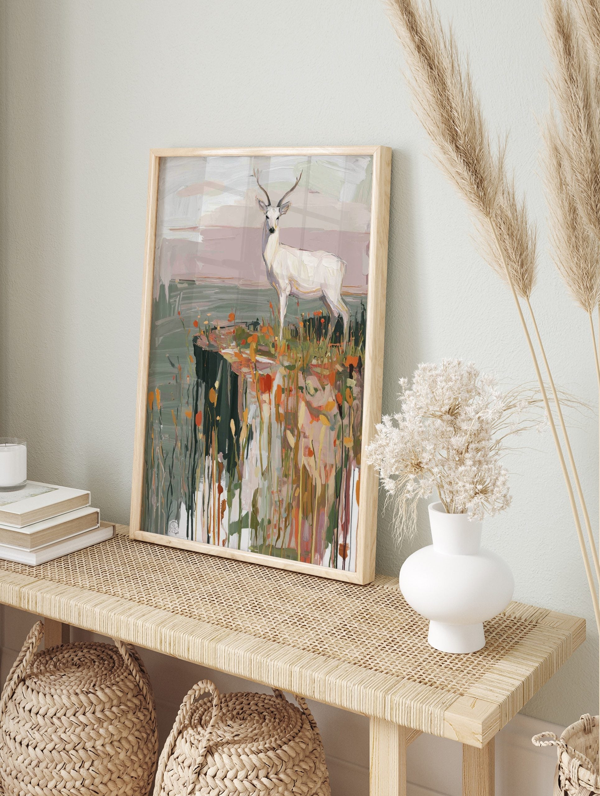 White deer with antlers standing on a cliff edge with orange and yellow grasses in a, in an alternate framed mockup