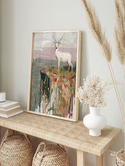 White deer with antlers standing on a cliff edge with orange and yellow grasses in a, in an alternate framed mockup