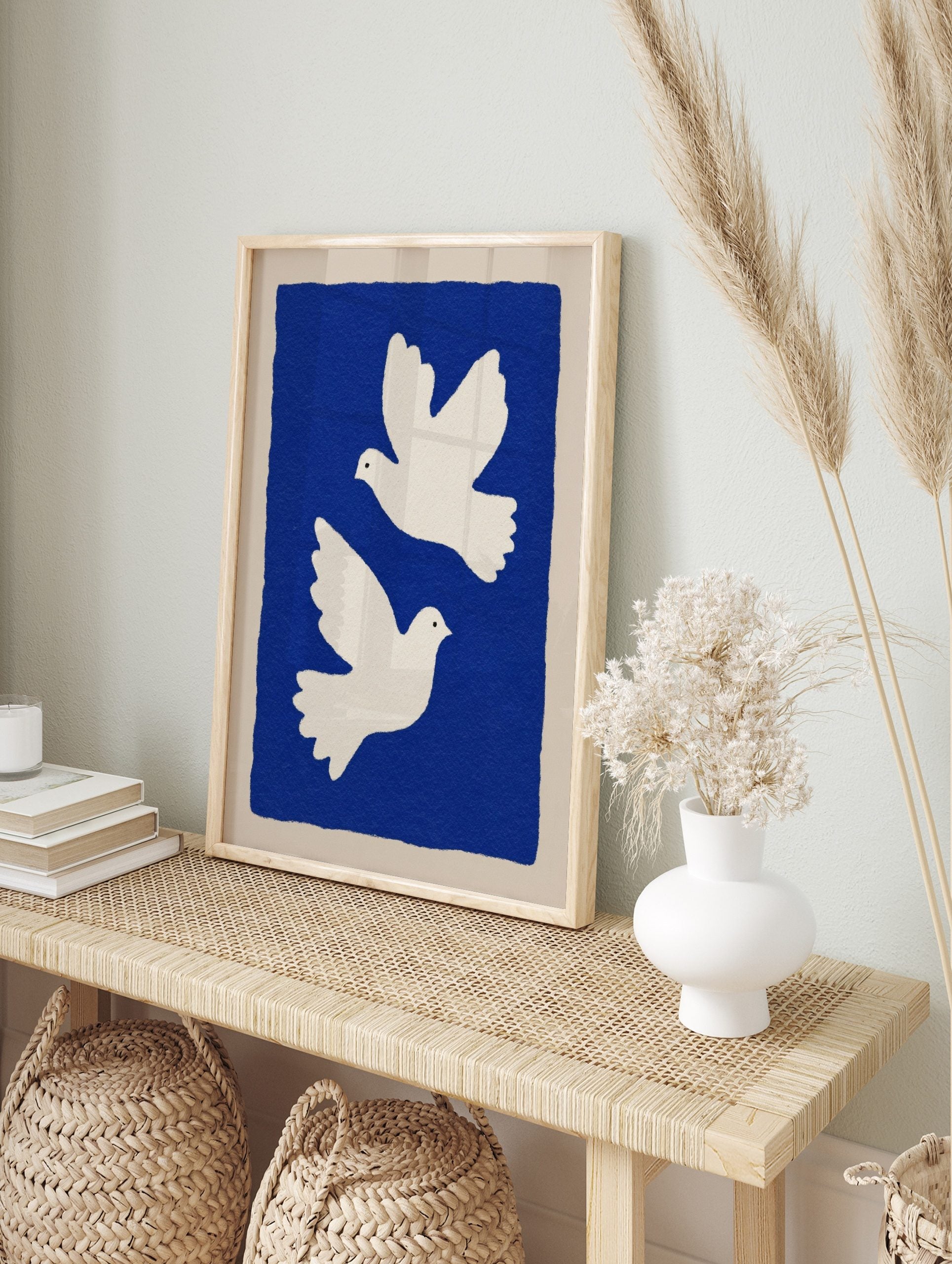 Two white illustrative doves flying against a deep blue background with a beige border, in an alternate framed mockup