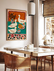 Illustrative print of three white ducks with croissants, coffee, and a vase on a teal and orange, in a styled room mockup