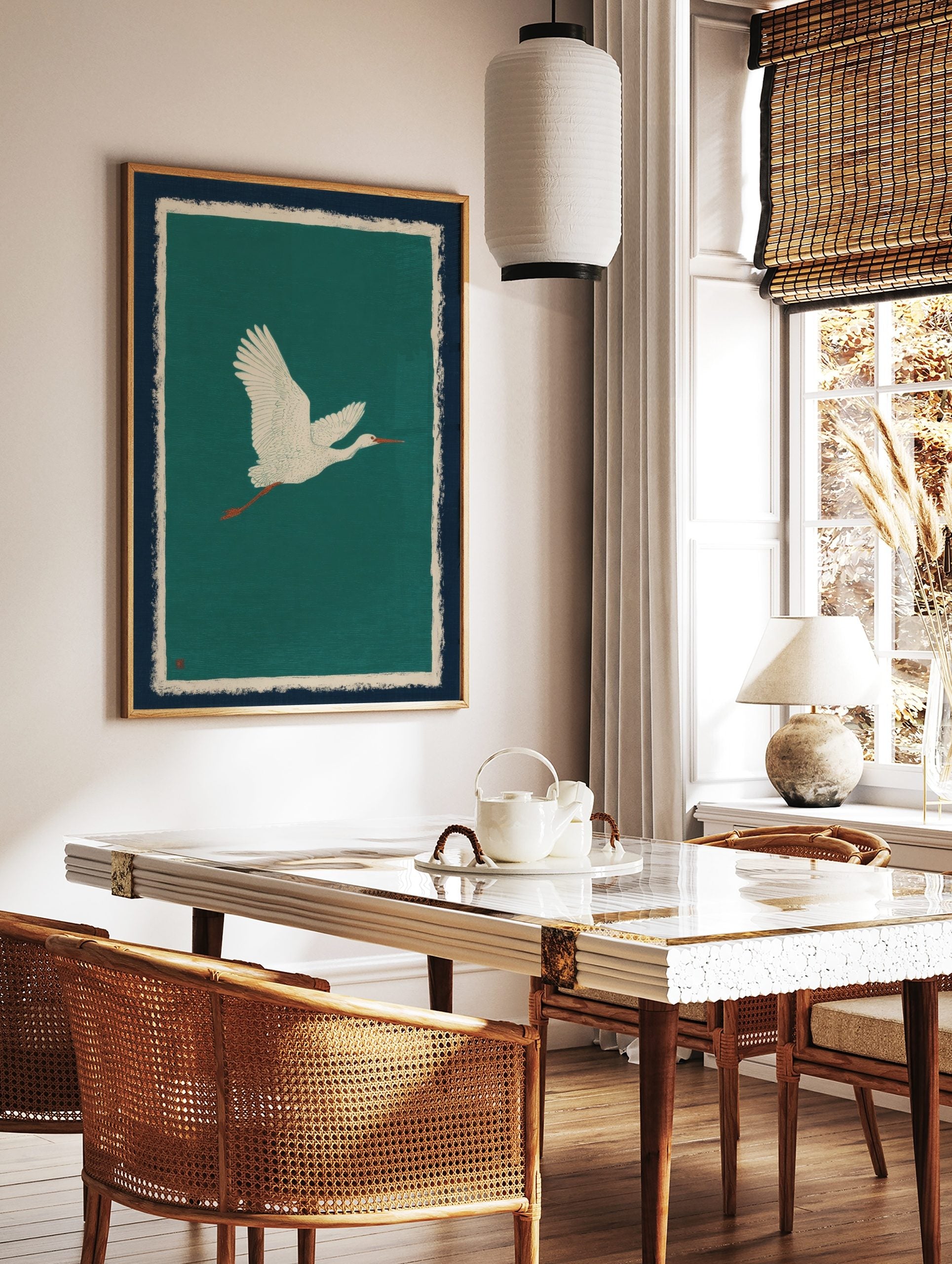 Illustrative white egret flying right against a teal background with navy and cream borders, in a styled room mockup