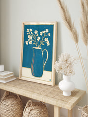 White flowers in a blue pitcher with gold outlines, a minimalist botanical illustration print, in an alternate framed mockup
