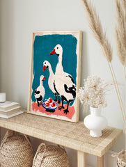 White geese family wall art with red beaks and black details on teal and pink background with, in an alternate framed mockup