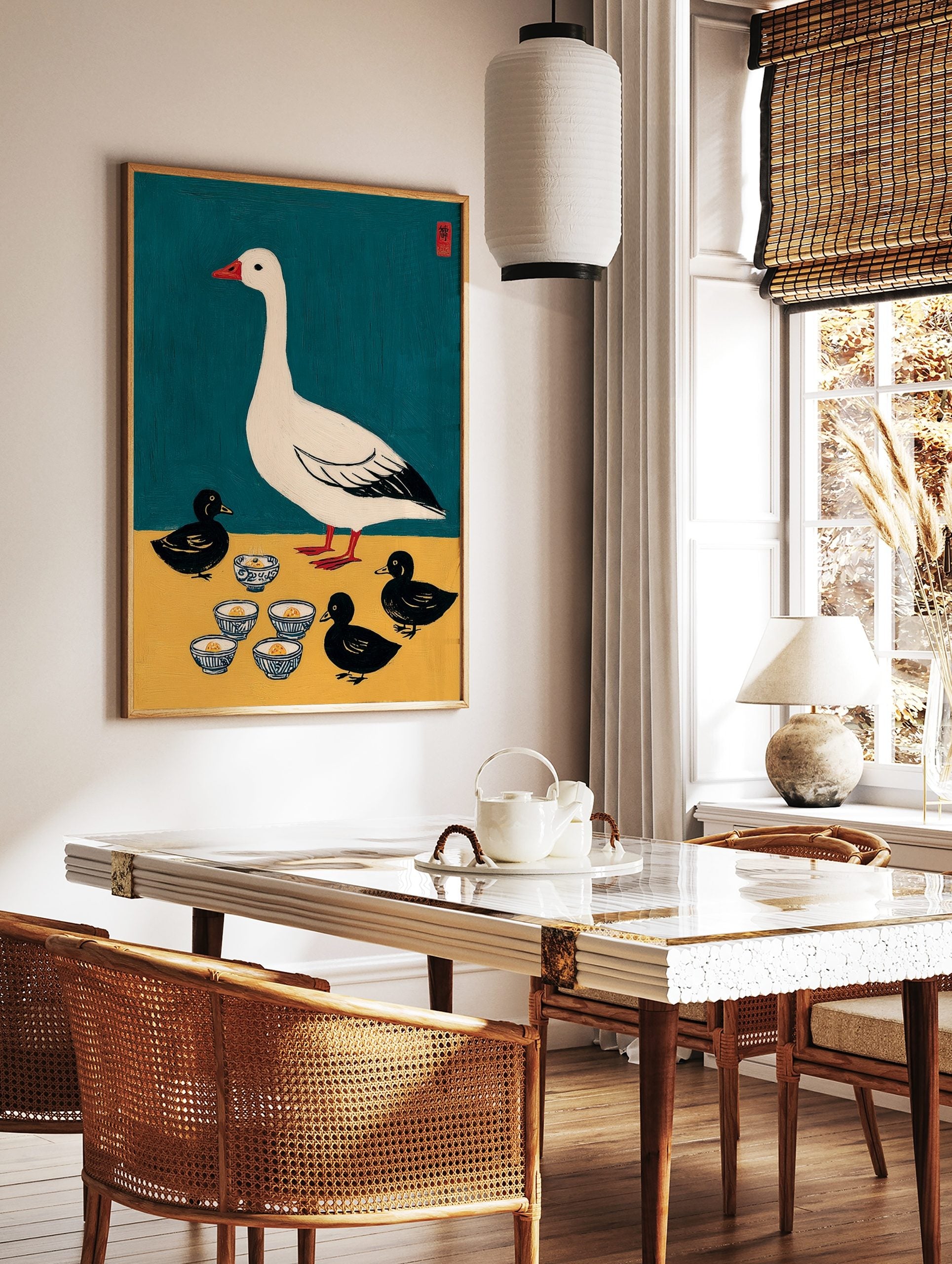 Illustrative print of a white goose and three black ducklings with patterned bowls on teal and, in a styled room mockup