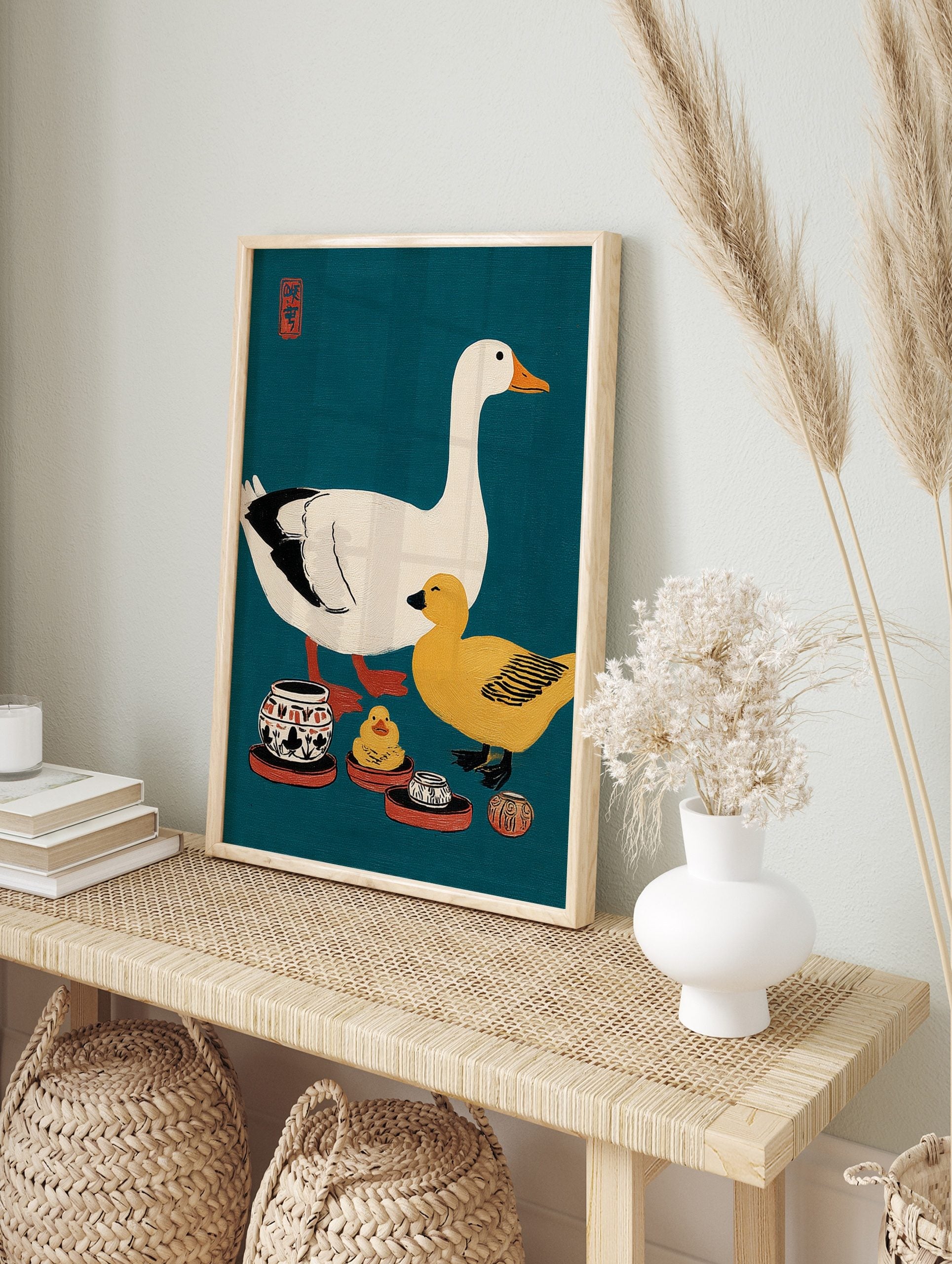 Illustrative print of a white goose, yellow duck, and ceramic pots on a teal background with, in an alternate framed mockup