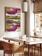 Modern landscape art print with green hills, wind turbines, purple water, and a purple and green sky, in a styled room mockup