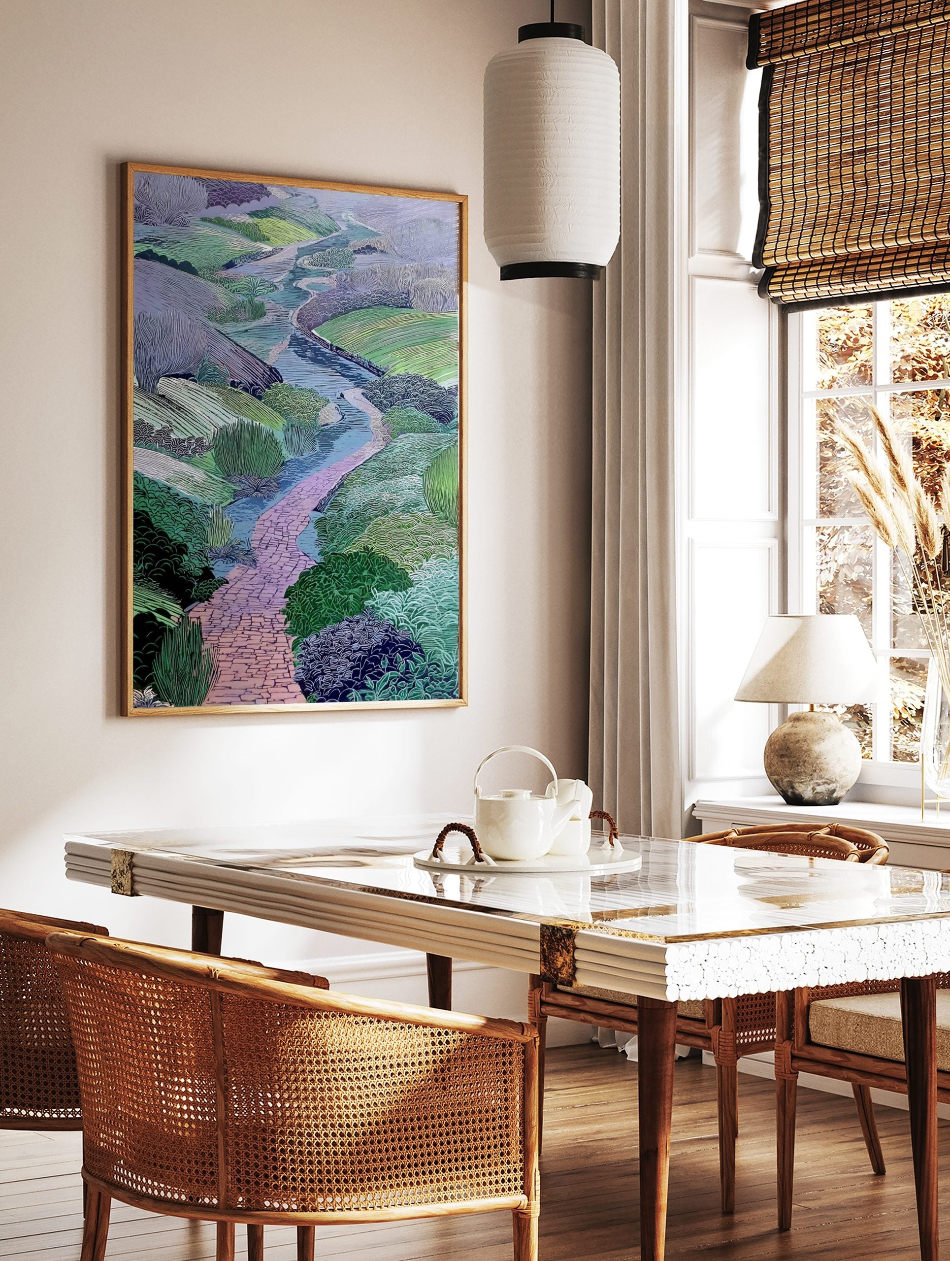 Illustrative landscape art print with a winding pink brick path, blue river, and green and purple, in a styled room mockup