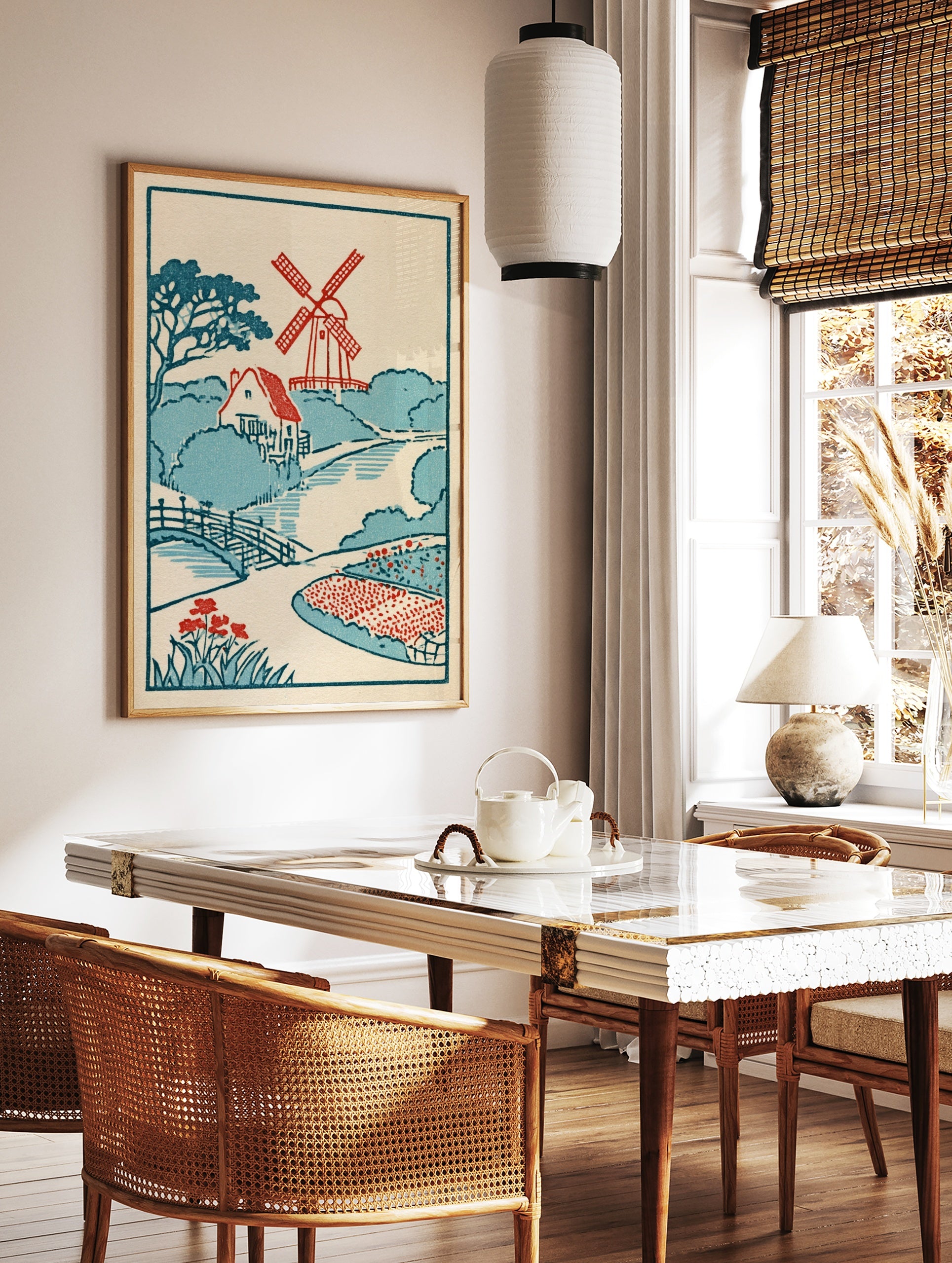 Vintage-style illustrative print featuring a red windmill, cottage, arched bridge, and red flowers, in a styled room mockup
