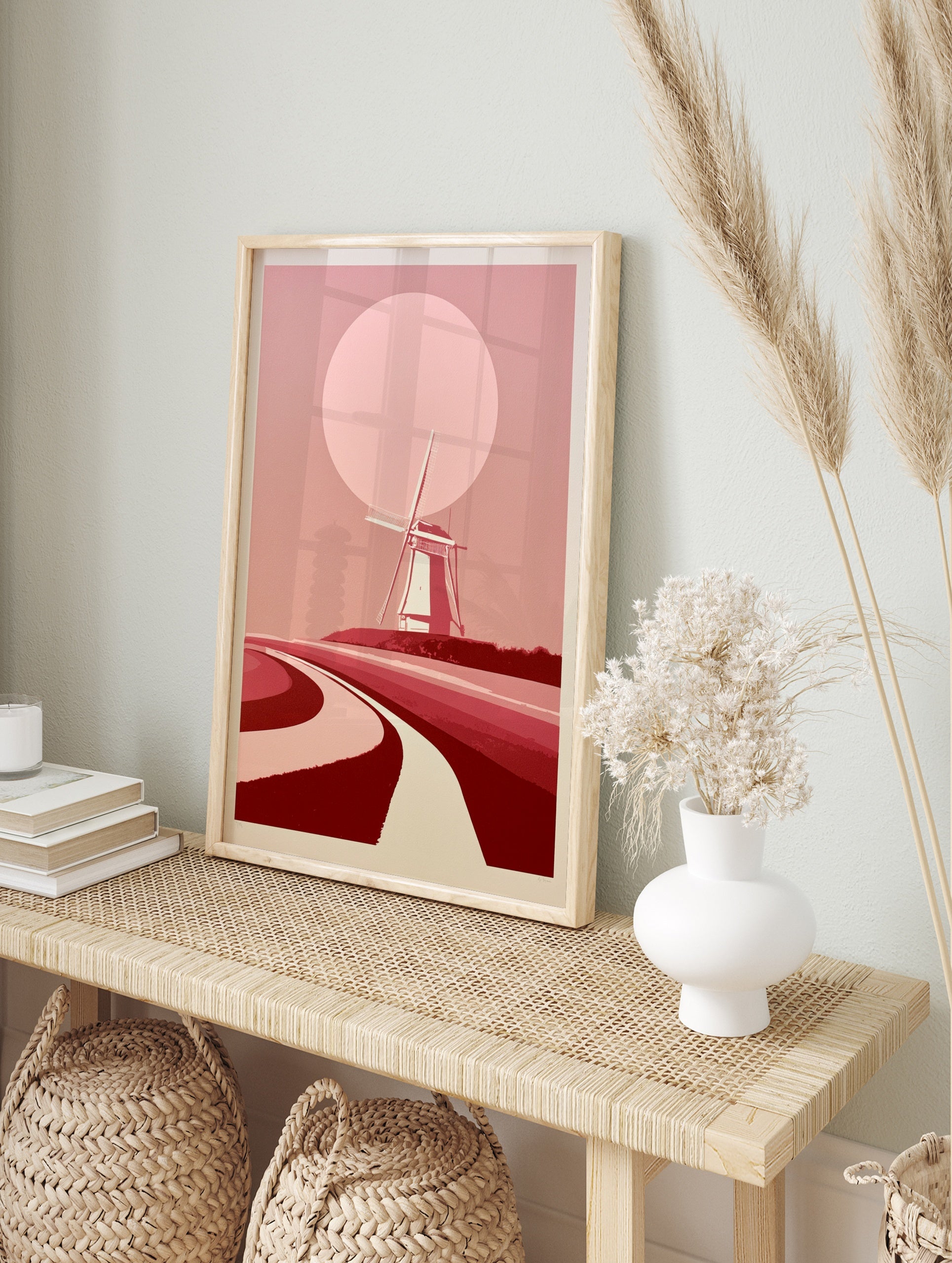 Minimalist windmill landscape wall art with a large pink sun and curved paths in shades of, in an alternate framed mockup
