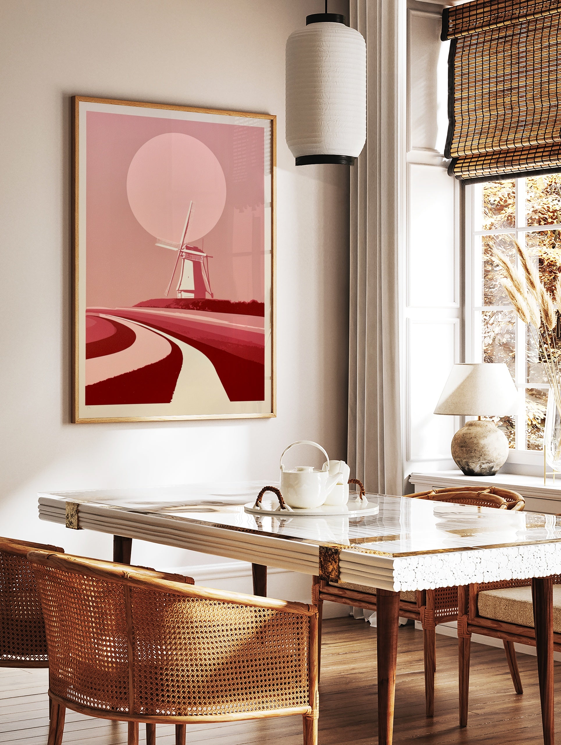 Minimalist windmill landscape wall art with a large pink sun and curved paths in shades of red and, in a styled room mockup