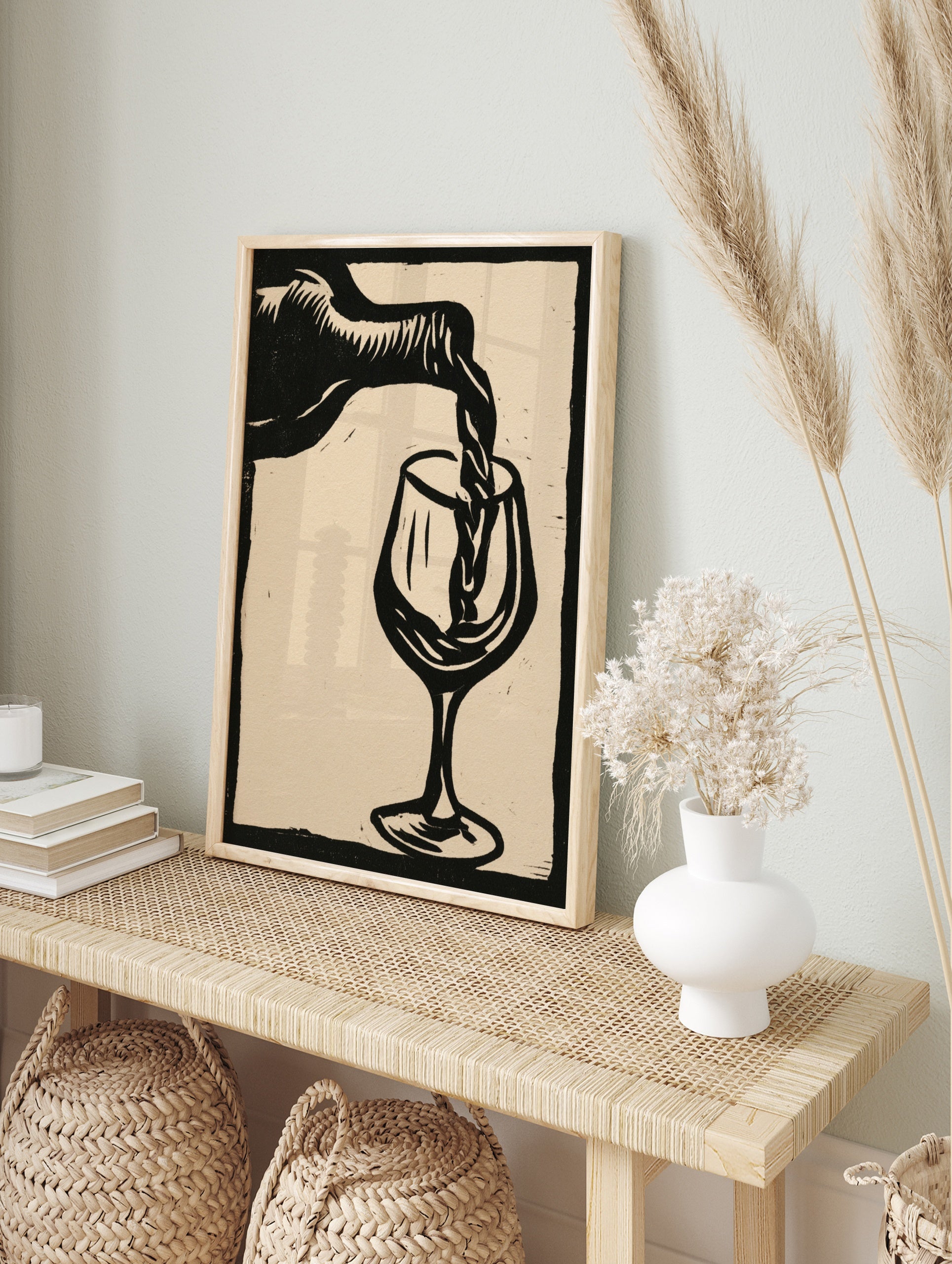 Linocut style black and white wall art of wine pouring into a glass on a neutral background, in an alternate framed mockup