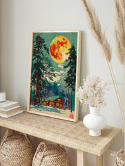 Illustrative print of a vibrant full moon over a snow-covered log cabin and tall pine trees, in an alternate framed mockup
