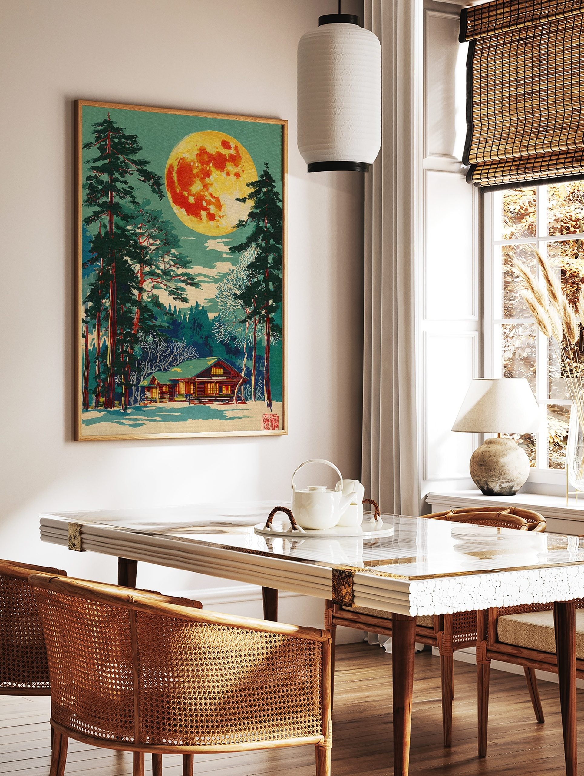 Illustrative print of a vibrant full moon over a snow-covered log cabin and tall pine trees at night, in a styled room mockup