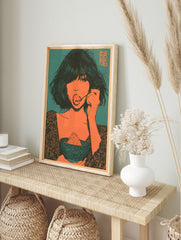 Illustrative art print of a woman eating dessert in orange and teal, featuring kanji text in, in an alternate framed mockup