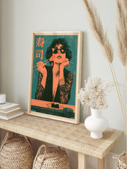 Retro style art print of a woman in sunglasses eating sushi with chopsticks and Japanese text, in an alternate framed mockup