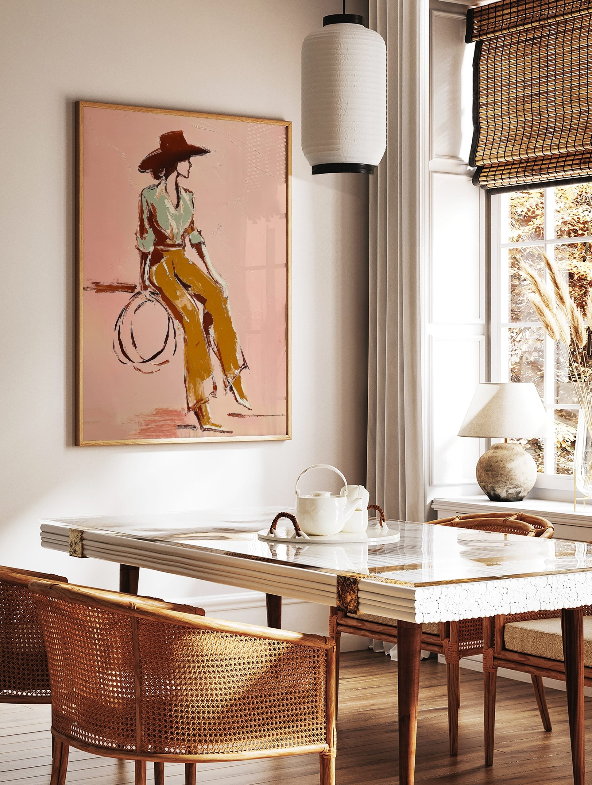 Illustrative print of woman in wide hat and ochre trousers against a pink background, in a styled room mockup