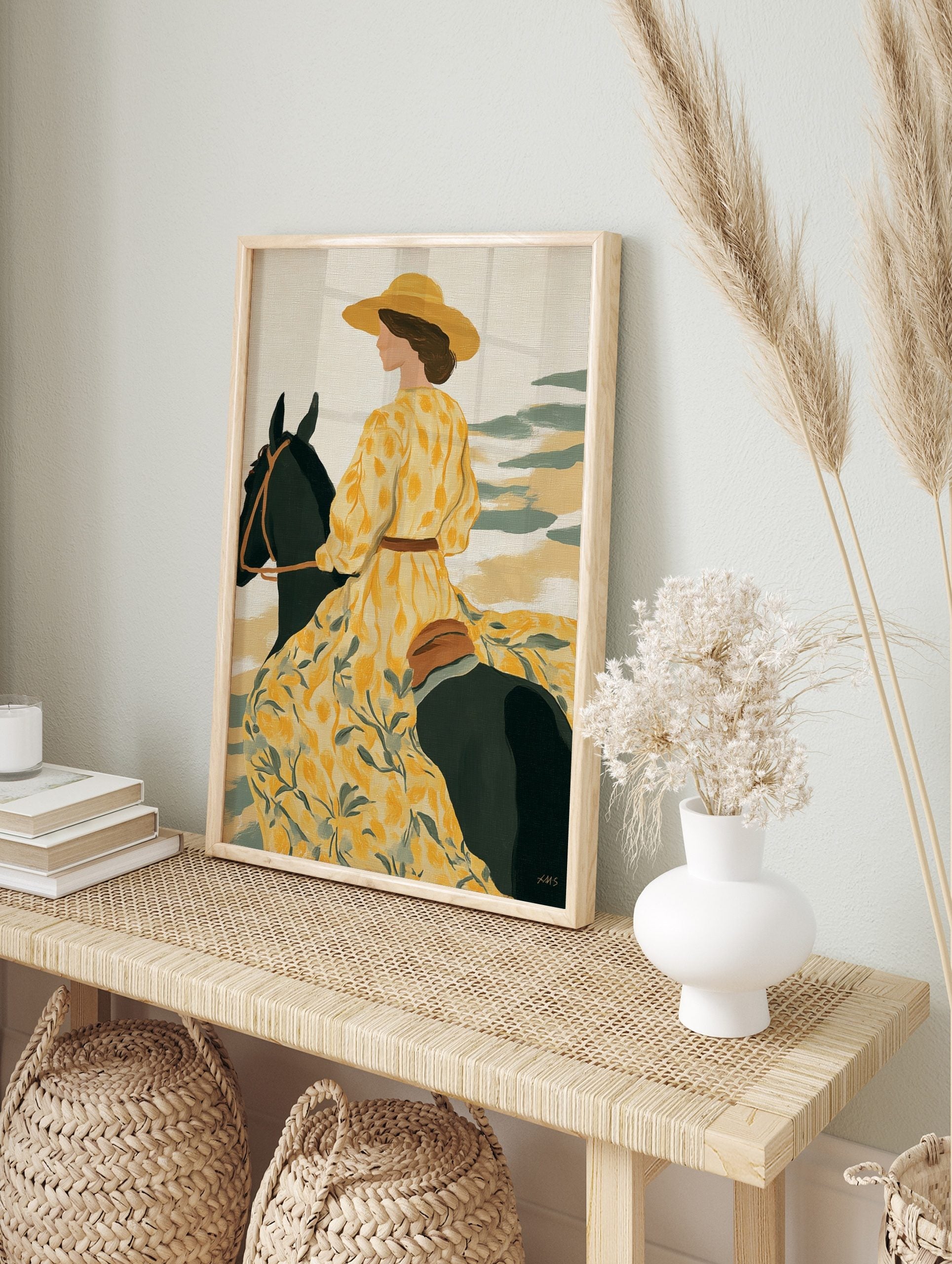 Illustrative art print of a woman in a yellow floral dress and hat riding a dark horse, in an alternate framed mockup