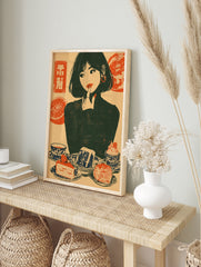 Retro illustrative wall art print of a woman with cake, citrus, and Japanese text on a cream, in an alternate framed mockup