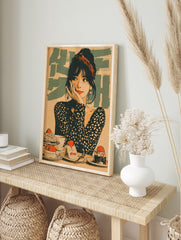 Retro illustrative wall art showing a woman with a red headband and polka dot top surrounded, in an alternate framed mockup