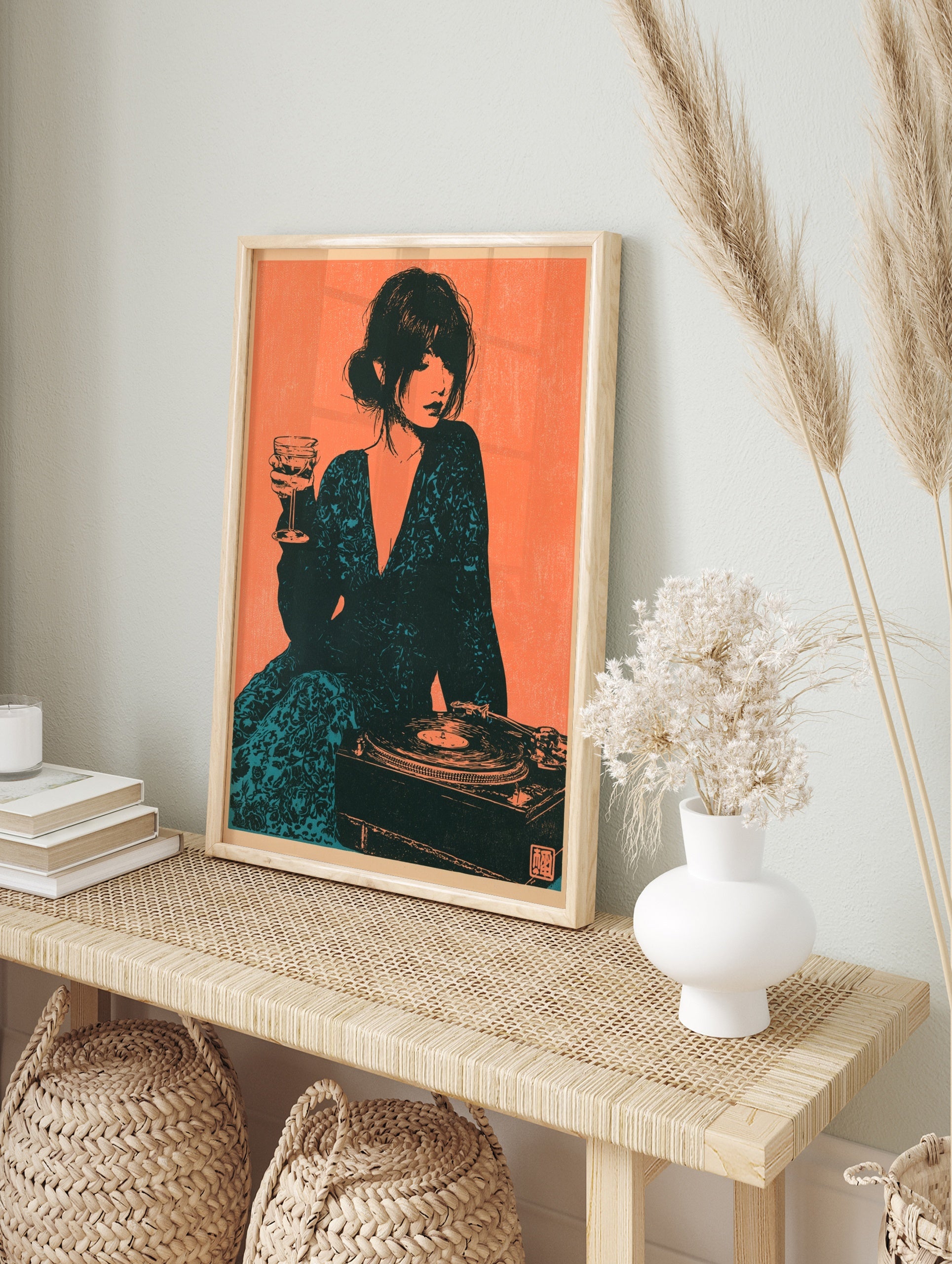 Illustrative art print of a woman holding a wine glass next to a record player in teal and, in an alternate framed mockup