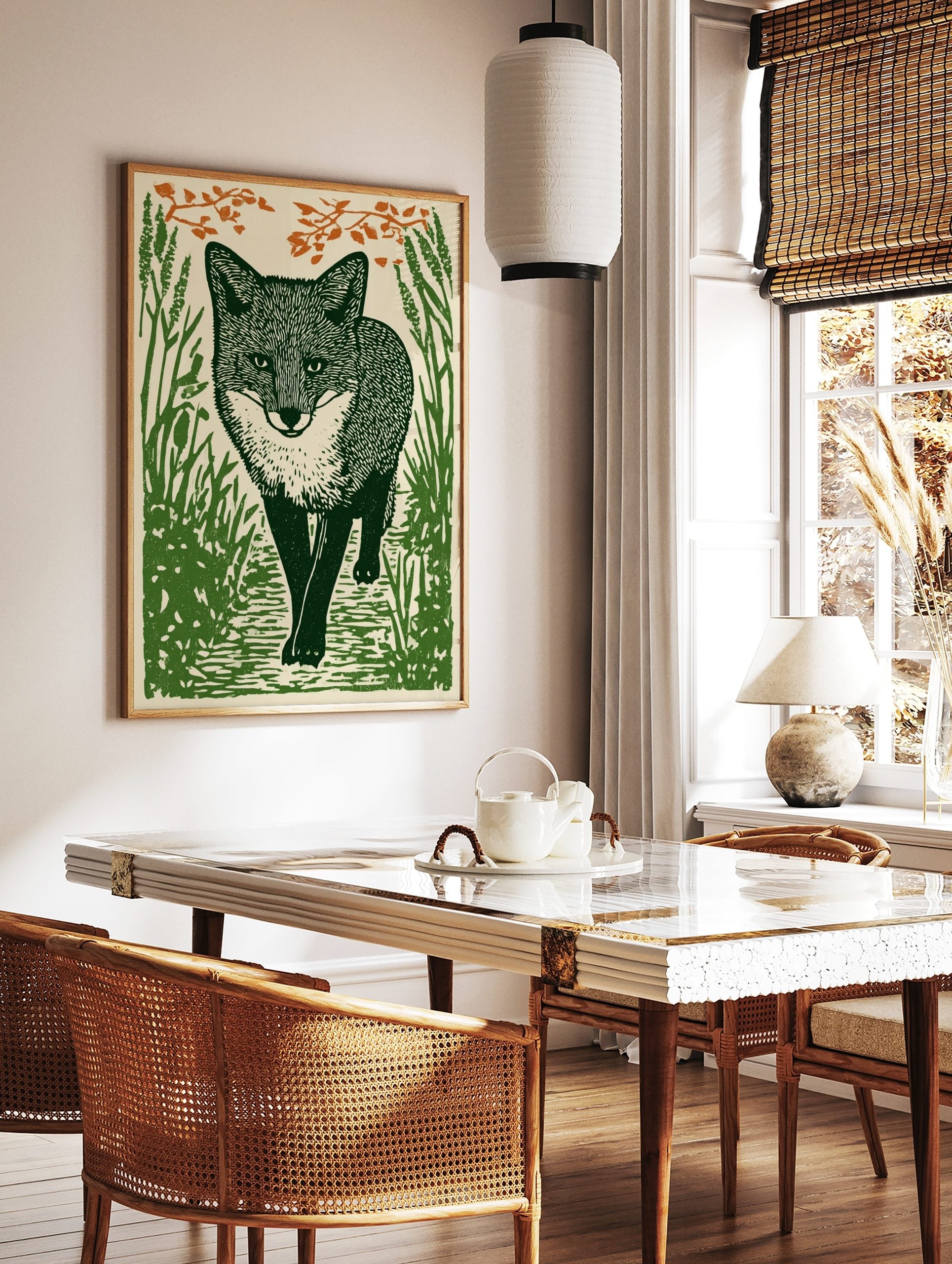Illustrative woodcut-style art print of a green fox walking through grass with orange leaves, in a styled room mockup