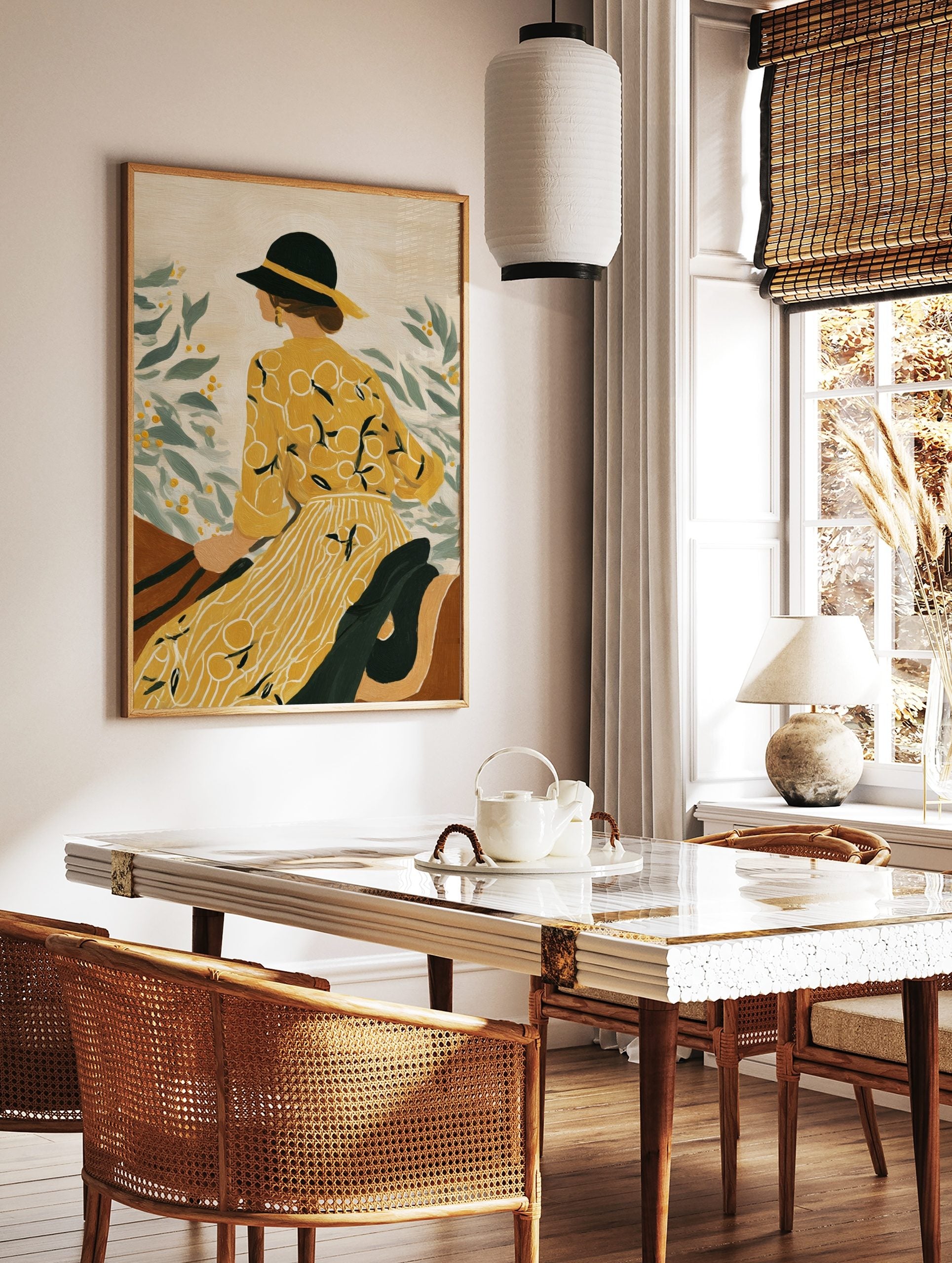 Illustrative art print of a woman in yellow dress and black hat, looking at green leaves with, in a styled room mockup