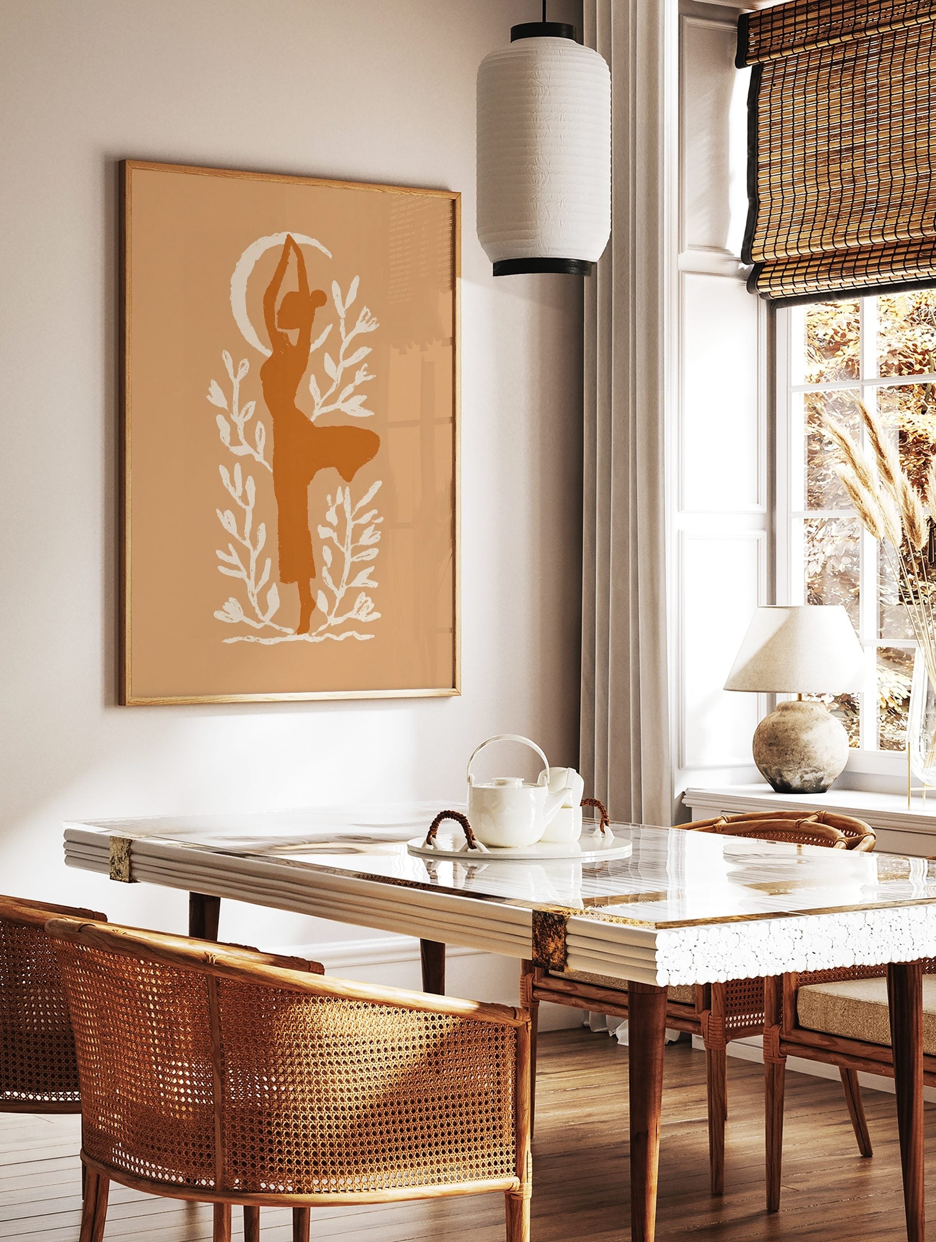 Stylised burnt orange silhouette of a woman in a yoga pose with a cream crescent moon and foliage, in a styled room mockup